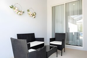 Une pièce moderne avec deux fauteuils en osier noir et une table basse en verre.