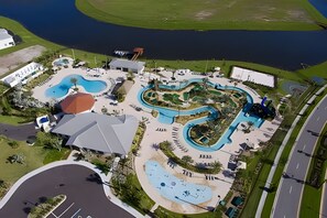 Vue aérienne d’un complexe hôtelier doté de plusieurs piscines, d’un grand bâtiment à toit rouge et d’une route adjacente à la propriété.