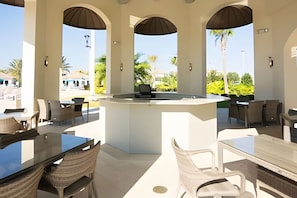 An outdoor patio area with a central island, surrounded by tables and chairs, offering views of the surrounding landscape. - 3BR Villa w/ Resort Access Near Disney (Davenport)