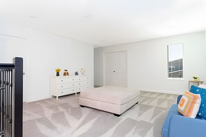Een slaapkamer met een bed, een dressoir, een kledingkast, een raam en een bank.