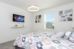 A modern bedroom with a large bed, a TV mounted on the wall, and artwork. - 9BR Villa w/ Pool & Game Room Near Disney (Davenport)