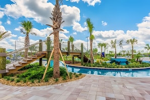 A pool area with a wooden staircase leading to a deck, surrounded by palm trees and a clear blue sky. - Storey Lake 4BR w/ Pool + Disney-themed Rooms (Kissimmee)