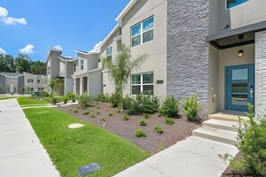 A modern apartment building with a well-maintained lawn and a stone facade. - Storey Lake 4BR w/ Pool + Disney-themed Rooms (Kissimmee)