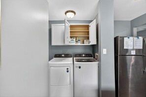 Ein kleiner Waschraum mit zwei Geräten für Frontlader und einem Kühlschrank aus Edelstahl.