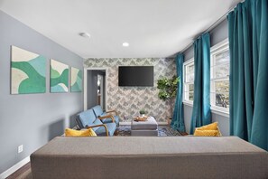 Una sala de estar moderna con sofá, reposapiés y una obra de arte en la pared.