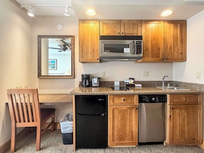A compact kitchen with wooden cabinets, a microwave, a coffee maker, and a dishwasher. - NEW - Stellar Location with Hot Tub, Pool, Steam Room & Gym Acces, Pets Okay (Crested Butte)