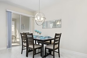 A dining area with a dark wooden table and chairs, a modern chandelier, and a large mirror on the wall. - Charming 4BR w/ Pool Near Disney - Storey Lake (Kissimmee)
