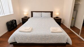 A neatly made bed with a patterned bedspread, two bedside lamps, and a folded towel on each side. - Ocean Escape | Beach Front Getaway, Steps to Sand (Redondo Beach)