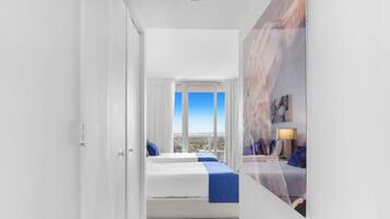 Habitación de hotel con un ventanal grande, una cama, un escritorio y vistas a la ciudad.