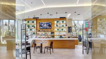 A bar area with a wooden counter, multiple shelves of bottles, and a television screen.