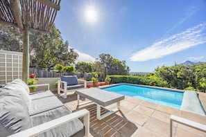 A poolside area with lounge chairs and a pergola.