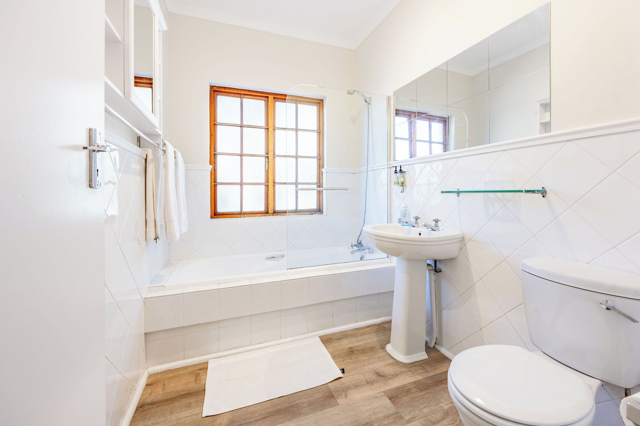 A modern bathroom with a bathtub, sink, toilet, and a window.