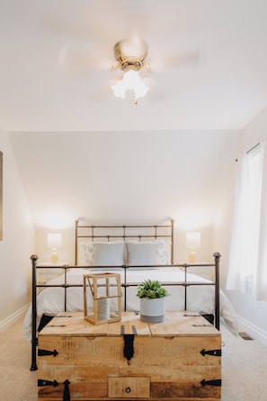 A bedroom with a metal bed frame, two bedside lamps, a wooden chest, and a ceiling light fixture. - Nordic Spa Lakefront Retreat | Sauna + Lake Plunge (Leeds and the Thousand Islands)