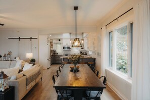 A modern kitchen with a central island, pendant lighting, and a view of the outdoors.