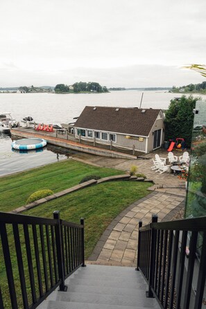 A waterfront property with a dock, a small building with a sloped roof, and a grassy area with outdoor seating.
