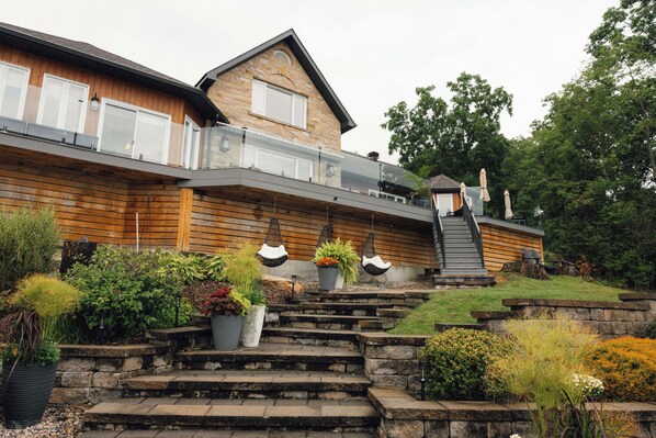 A two-story house with a stone facade, a balcony, and a set of stone steps leading to the entrance.
