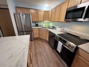 Una cocina moderna con electrodomésticos de acero inoxidable, armarios de madera y encimera de mármol.