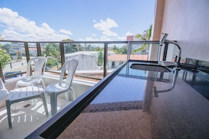 A balcony with a glass barrier, a sink, and white plastic chairs. - IBIZA Ap. 209 Balta (Ipojuca)