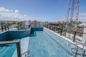 A rooftop swimming pool with a glass barrier, surrounded by buildings and a clear sky. - IBIZA Ap. 209 Balta (Ipojuca)