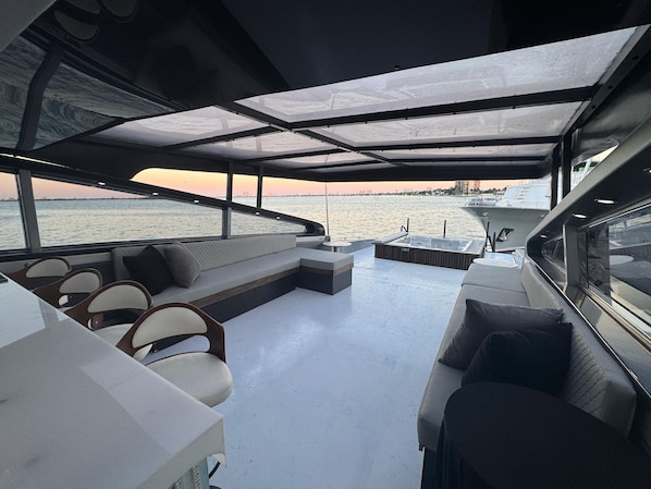 A boat interior with a seating area, a hot tub, and a view of the water.