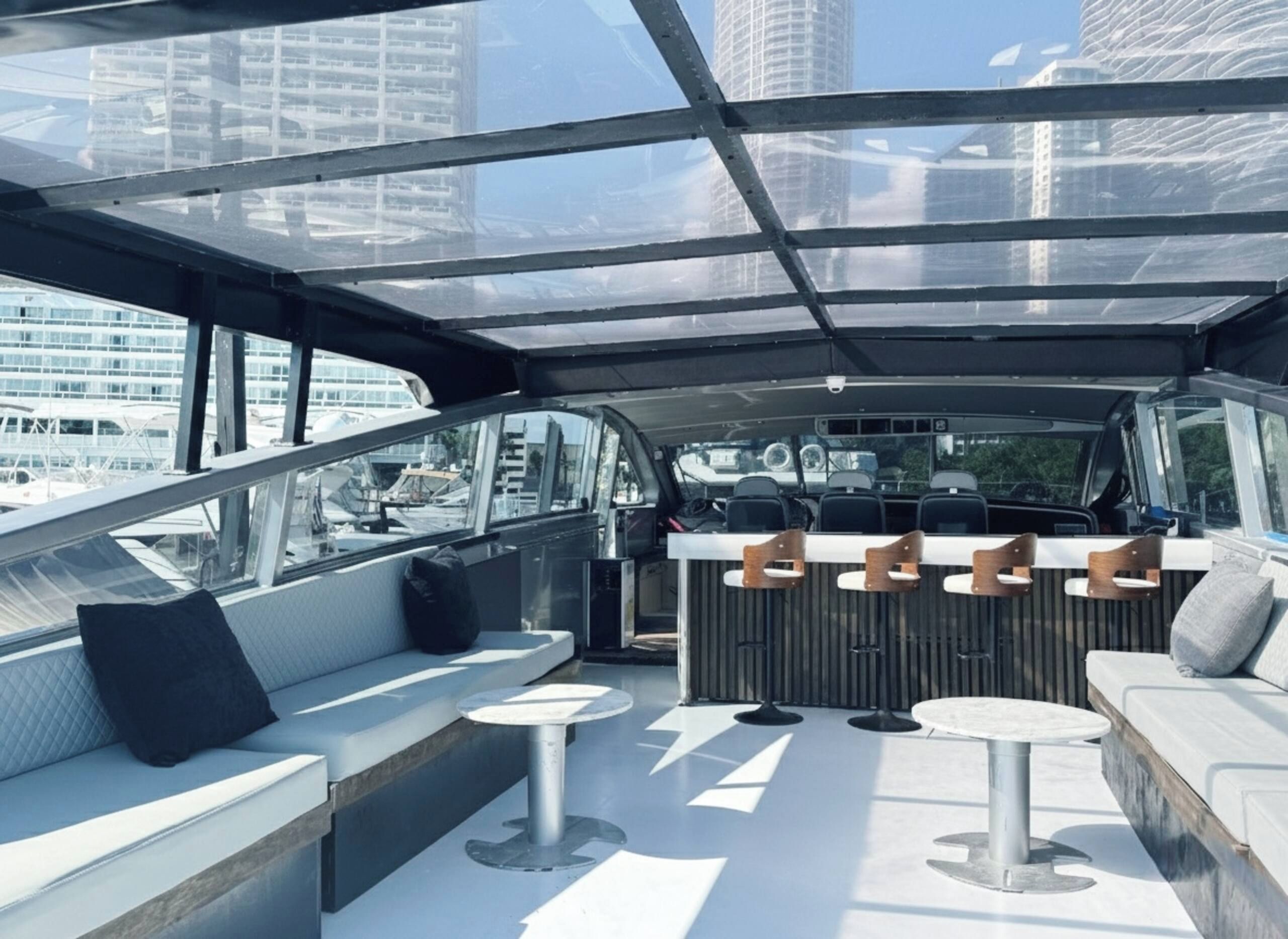 Un intérieur de bateau moderne avec un bar, des sièges et de grandes fenêtres offrant une vue sur la ville.