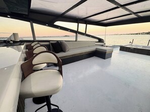 A boat deck with seating areas, a table, and a view of the water.