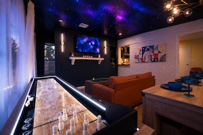 A billiards table with balls, a sofa, a television, and a wall with a space-themed mural. - Space City | Work Stays • Family Fun • 3BR (Weatherford)