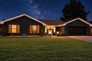 A two-story house with a dark exterior, a front porch with seating, and a garage.