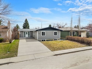 A residential house with a front yard, a driveway, and a clear sky. - cozy Oakmoor Way House (Calgary)