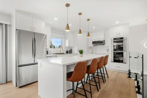A modern kitchen with a central island, stainless steel appliances, and pendant lighting. - cozy Oakmoor Way House (Calgary)