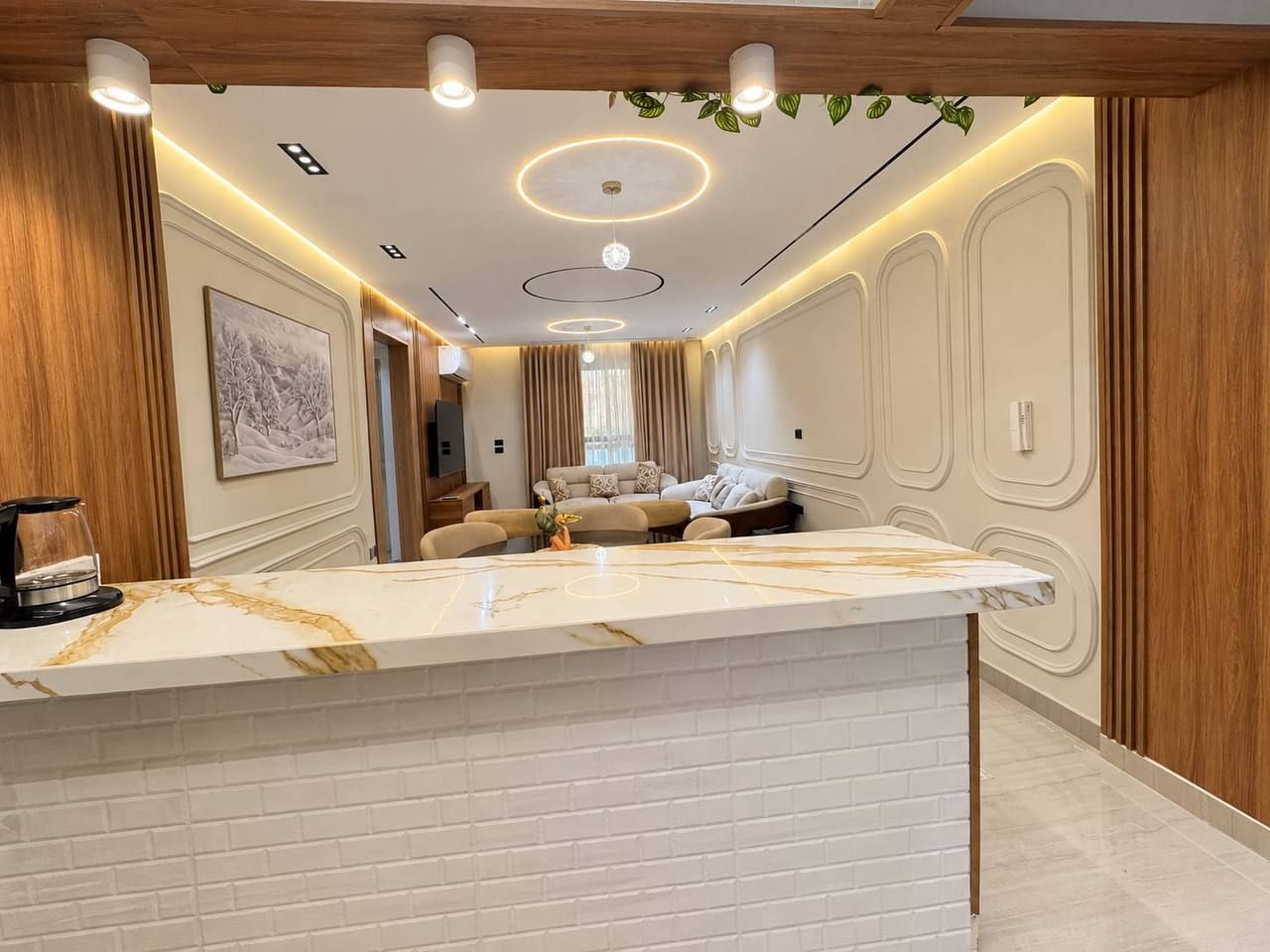 Una cucina moderna con piano di lavoro in marmo, rivestimento in legno e illuminazione a incasso.