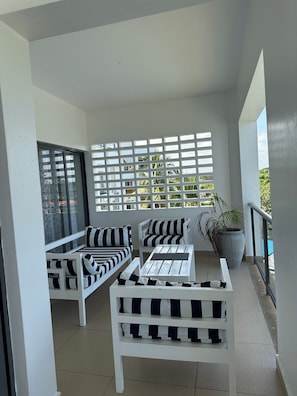 A balcony with white furniture, including a sofa and a chair, and a potted plant. - Xanadu Beachfront Apartments (Mombasa)