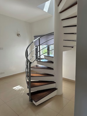 A spiral staircase with wooden steps and metal railings, leading to an upper floor. - Xanadu Beachfront Apartments (Mombasa)