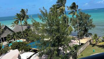 A resort with a pool, palm trees, and a view of the ocean.