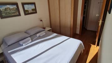 Un dormitorio con cama, armario de madera y dos cuadros en la pared.
