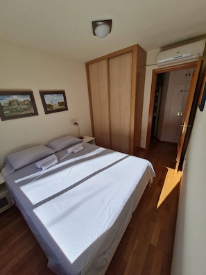 A bedroom with a bed, wooden wardrobe, and two framed pictures on the wall. - Great Apartment in Madrid (Madrid)