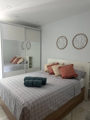 Un dormitorio con cama, almohadas, un espejo y decoración en la pared.