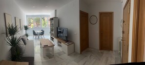 Ett modernt vardagsrum med tv, sittgrupp och ett matbord.