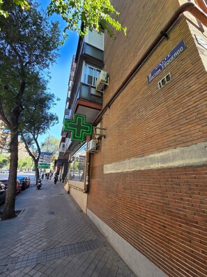 A brick building with a green cross sign indicating a medical facility. - Beautiful Apartment in Retiro (Madrid)