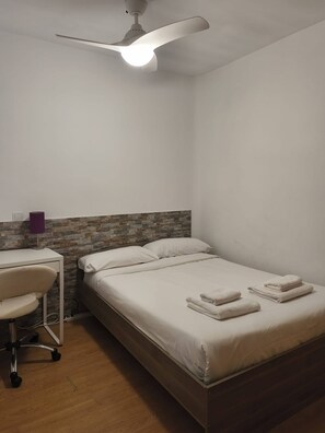 A bedroom with a bed, a desk, a chair, a ceiling fan, and a wall with a textured pattern. - Apartment in Fuente del Berro (Madrid)