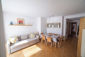 A living room with a sofa, dining table, and chairs. There is a hallway leading to another room. - Flat with parking in the center of Las Rozas (Las Rozas)