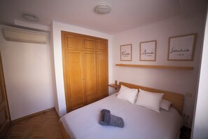 Un dormitorio con una cama, un armario de madera y tres carteles enmarcados en la pared.