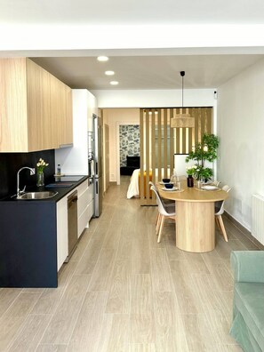 A modern kitchen with a central island, a dining area with a round table, and a visible bedroom with a bed and a window. - Fabulous Apartment in Madrid (Madrid)