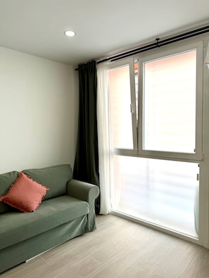 A room with a green sofa, a red pillow, and a large window with curtains. - Fabulous Apartment in Madrid (Madrid)