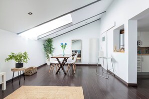 Un interior modern amb zona de menjador, cuina i saló d'estar amb sostre alt i gualtra.