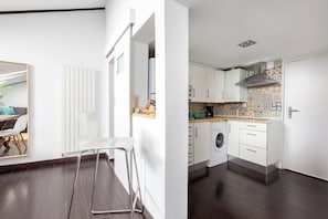Una cuina moderna amb armaris blancs, una rentadora i un relleu decoratiu a la paret.