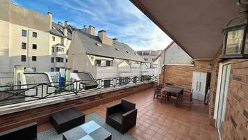 Une terrasse sur le toit, aménagée avec du mobilier d’extérieur, offrant une vue sur les bâtiments environnants et un ciel dégagé.