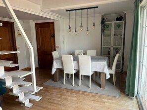 Zona de menjador amb taula, cadirees i llum penjant.