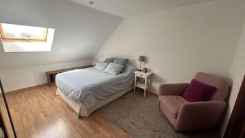 Une chambre à coucher avec un lit, une table de chevet, une chaise et une lucarne.