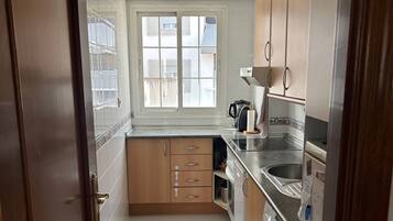 Une cuisine de taille réduite, équipée d’un lave-linge, d’une fenêtre et d’une porte.